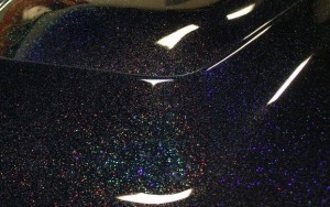 Black holographic metal flakes on a car hood. Holographic flakes.