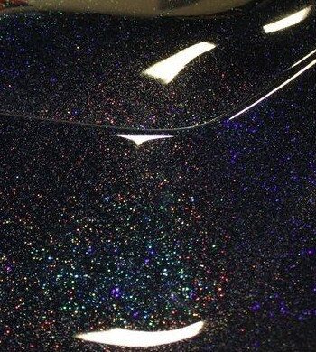 Black holographic flake on a car hood.